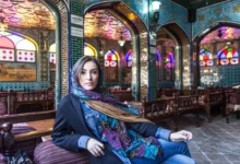 Woman Sitting In Colourful Restaurant With Stained Glass Windows